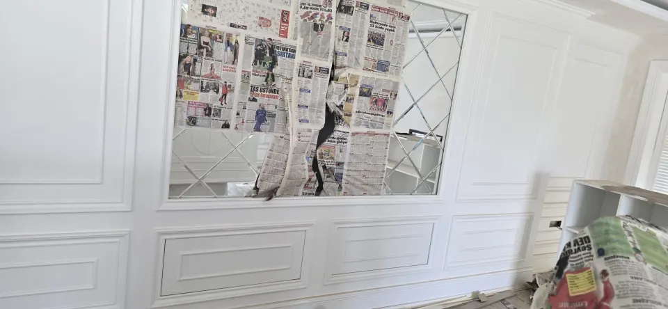 Villa dekorasyonu sırasında gazeteyle korunan aynalı duvar ve beyaz profilli boiserie paneller